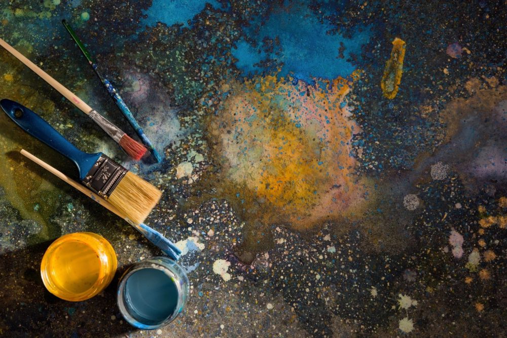 Paint brushes lying next to open paint cans